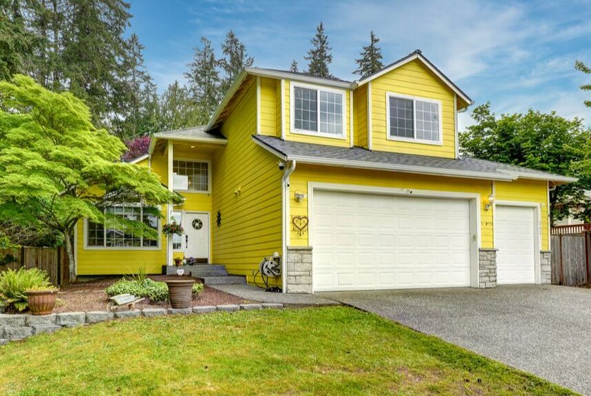 Adorable yellow exterior of the 2-story home with 3-car garage.