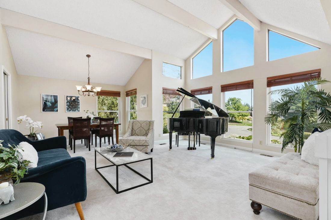 Huge front yard and blue 1-story home with treed background