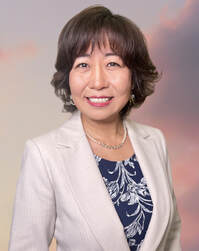 Mayumi Shimizu Real Estate wearing a beige jacket and dark blue shirt smiling at camera